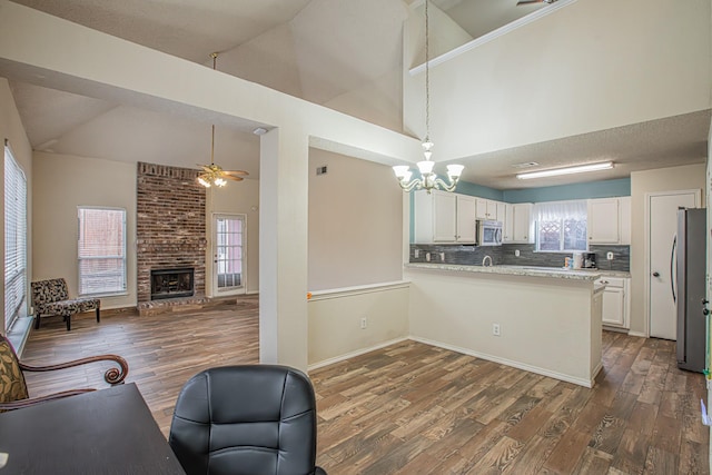 kitchen with a peninsula, dark wood-type flooring, white cabinetry, open floor plan, and appliances with stainless steel finishes