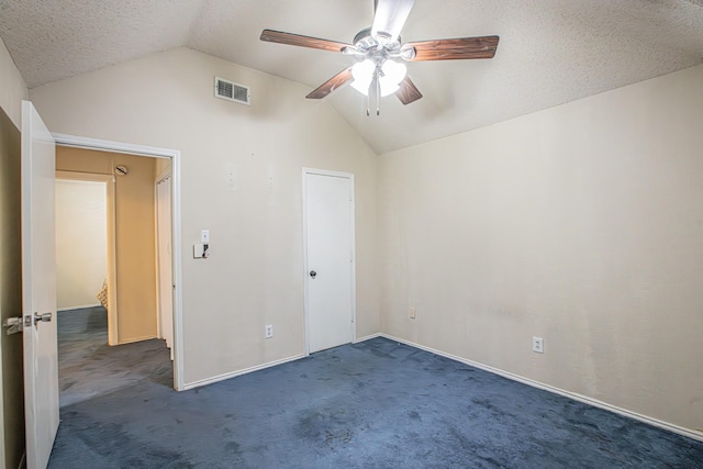 unfurnished bedroom featuring visible vents, ceiling fan, vaulted ceiling, a textured ceiling, and carpet floors