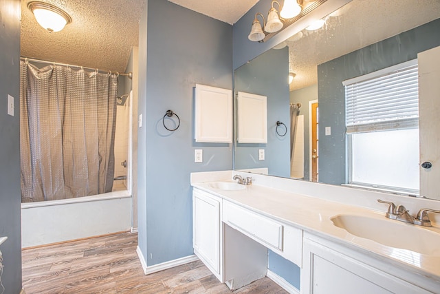 bathroom featuring a textured ceiling, shower / bath combination with curtain, wood finished floors, and a sink