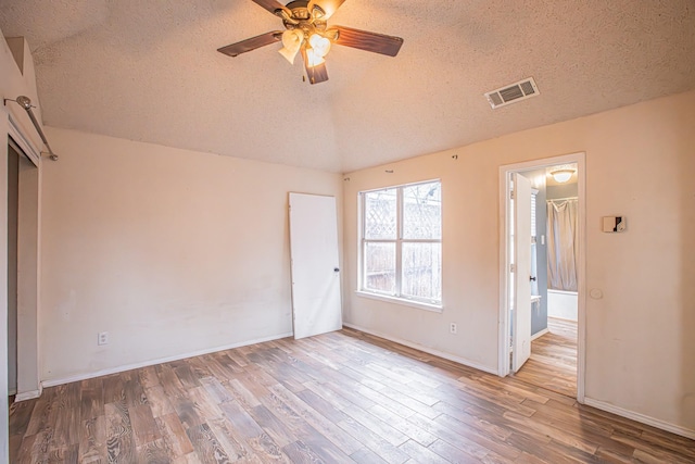 empty room with ceiling fan, a textured ceiling, visible vents, and wood finished floors