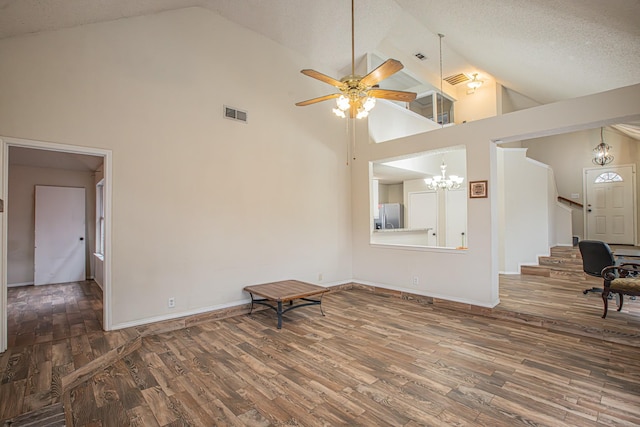 unfurnished living room with a textured ceiling, wood finished floors, high vaulted ceiling, baseboards, and ceiling fan with notable chandelier