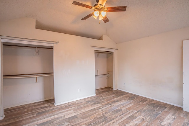 unfurnished bedroom with ceiling fan, a textured ceiling, vaulted ceiling, and wood finished floors