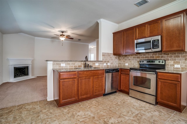 kitchen with stainless steel appliances, a sink, visible vents, tasteful backsplash, and brown cabinetry