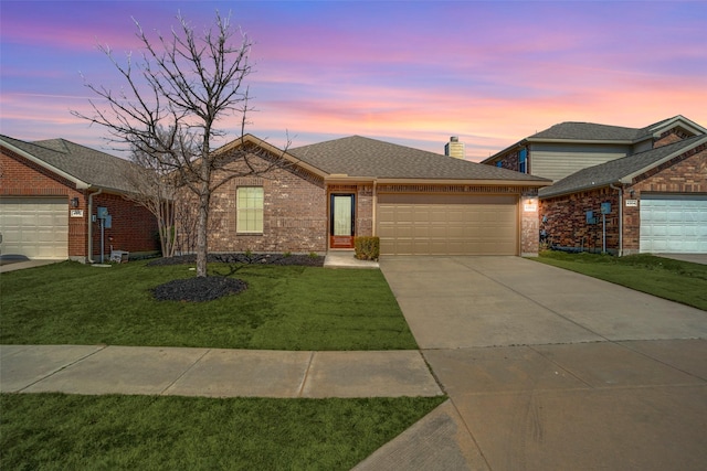 ranch-style home with concrete driveway, a chimney, an attached garage, a yard, and brick siding