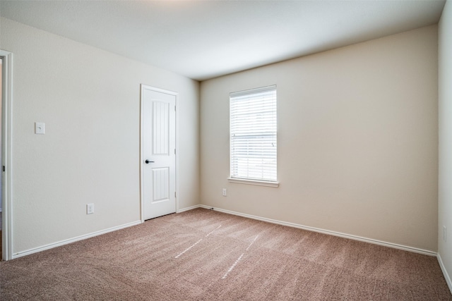 spare room with light colored carpet and baseboards