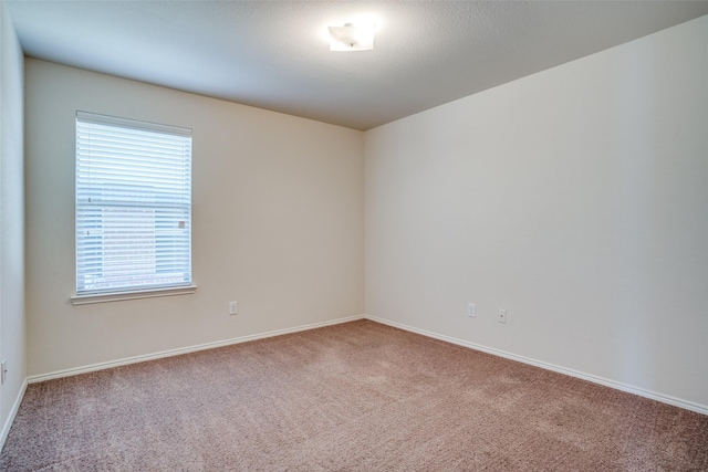 carpeted spare room featuring baseboards