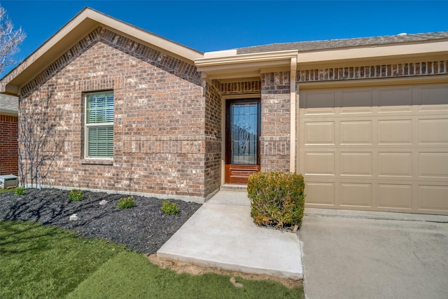 view of exterior entry featuring a garage and brick siding