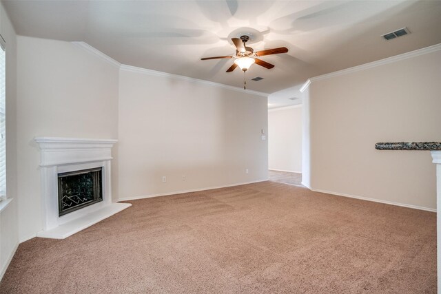 unfurnished living room featuring ornamental molding, carpet flooring, a fireplace with raised hearth, visible vents, and a ceiling fan