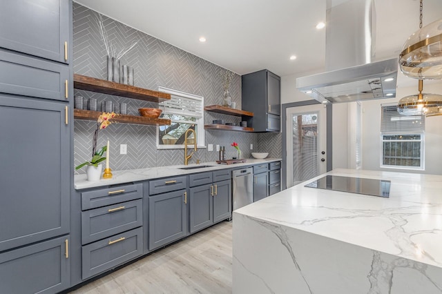 kitchen with island exhaust hood, open shelves, light stone counters, tasteful backsplash, and a sink