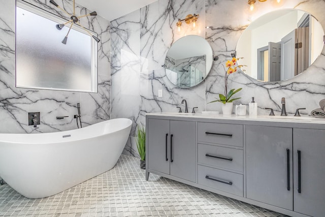 full bathroom with a freestanding bath, double vanity, stone wall, and a sink