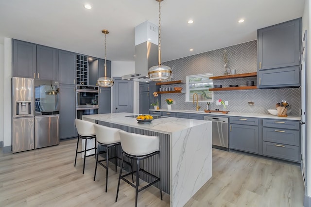 kitchen with a kitchen island, a breakfast bar, light stone counters, appliances with stainless steel finishes, and open shelves