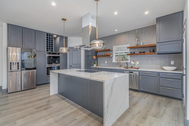 kitchen with a center island, light stone countertops, light wood-style flooring, appliances with stainless steel finishes, and open shelves