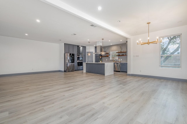 unfurnished living room with recessed lighting, an inviting chandelier, baseboards, and light wood-style floors