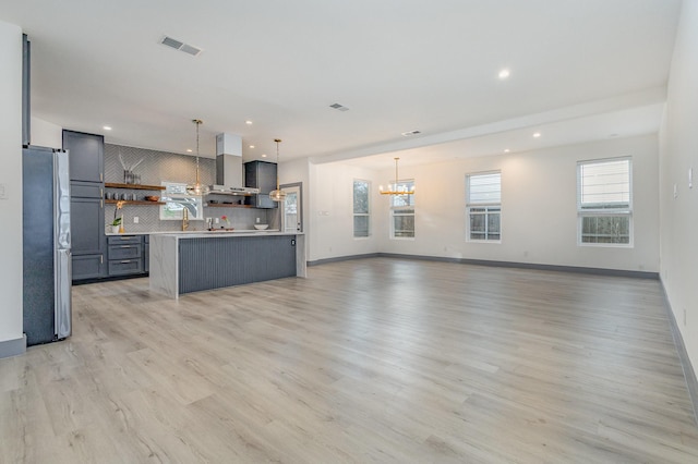 kitchen with visible vents, open shelves, freestanding refrigerator, wall chimney exhaust hood, and open floor plan