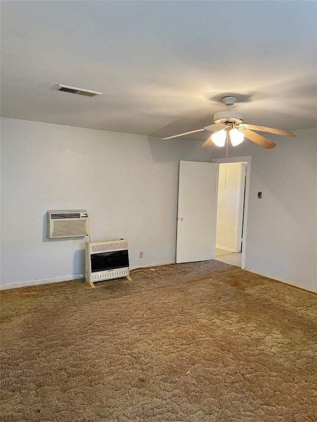 spare room featuring a ceiling fan, carpet, visible vents, and heating unit