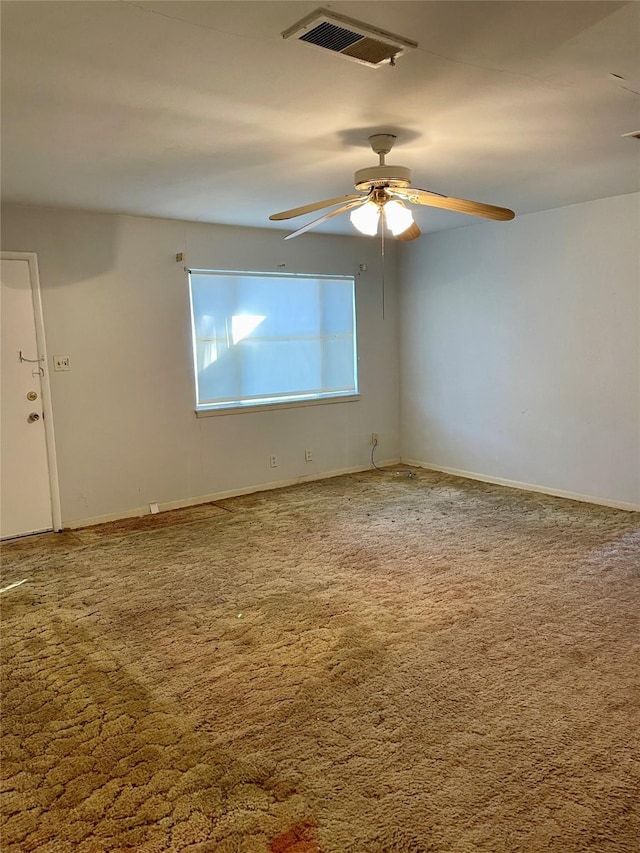 spare room with carpet, ceiling fan, visible vents, and baseboards