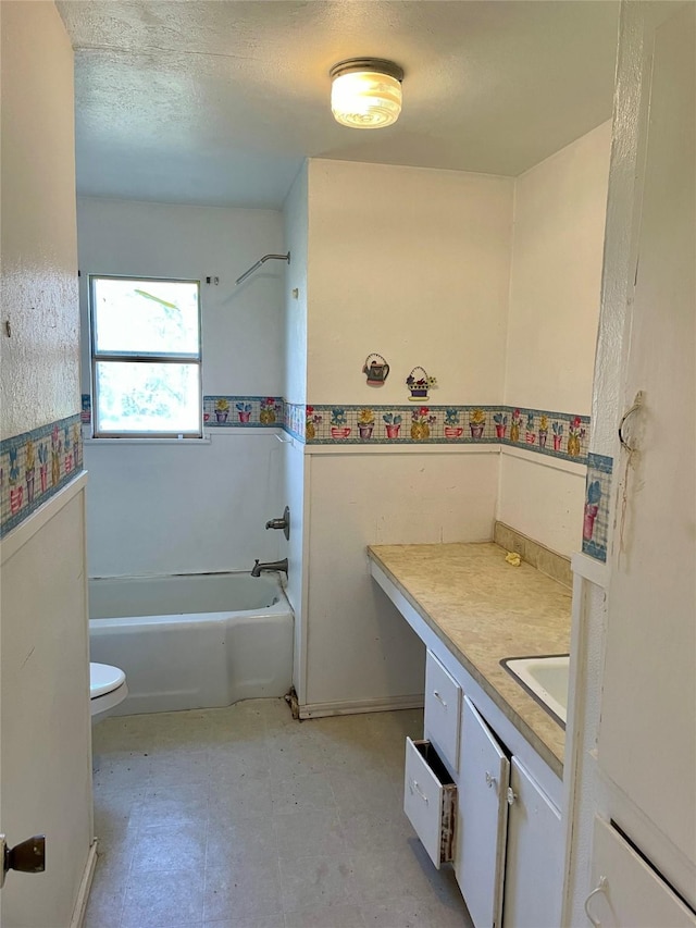 bathroom with a textured ceiling, toilet, vanity, shower / washtub combination, and tile patterned floors