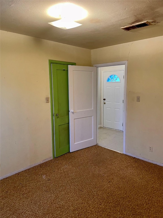 carpeted empty room featuring visible vents and a textured ceiling