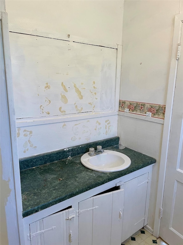 bathroom with tile walls, a wainscoted wall, and vanity