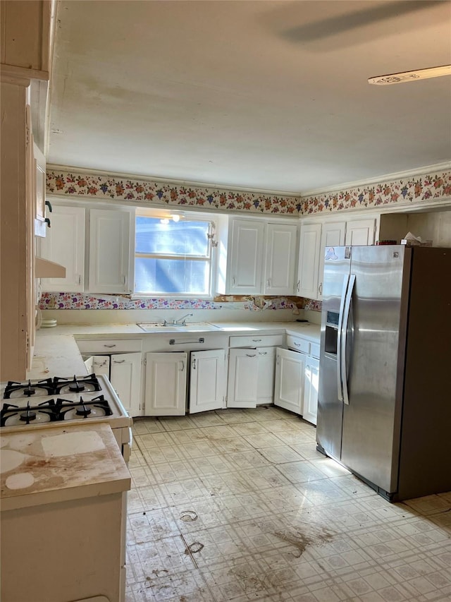 kitchen with white cabinets, stainless steel refrigerator with ice dispenser, a sink, and light countertops