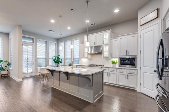 kitchen featuring appliances with stainless steel finishes, white cabinetry, visible vents, and under cabinet range hood