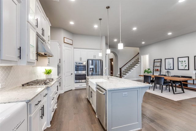 kitchen featuring appliances with stainless steel finishes, arched walkways, dark wood-type flooring, and white cabinetry