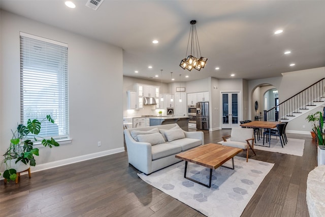 living room with arched walkways, dark wood-style floors, stairs, and recessed lighting