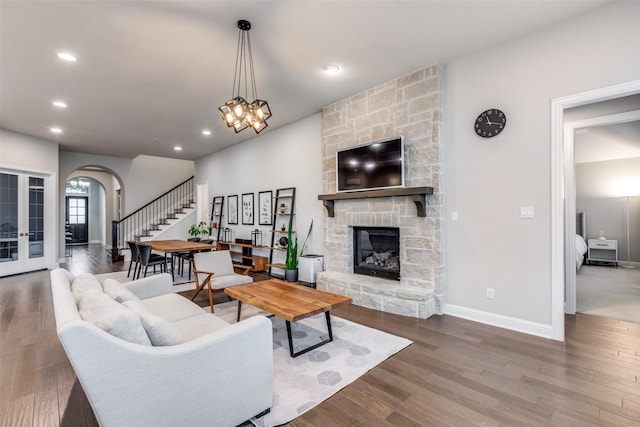 living area featuring arched walkways, a fireplace, recessed lighting, wood finished floors, and stairs