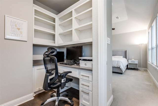 office area featuring built in desk, dark wood finished floors, visible vents, and baseboards