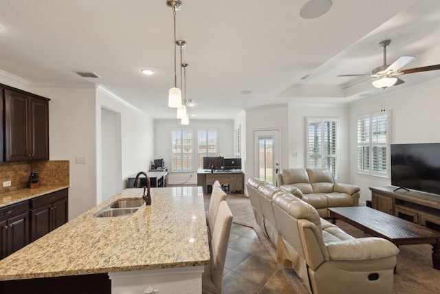 kitchen with tasteful backsplash, visible vents, open floor plan, dark brown cabinets, and a sink