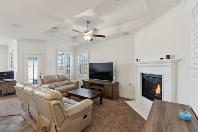 living room with carpet floors, a raised ceiling, crown molding, and a tile fireplace