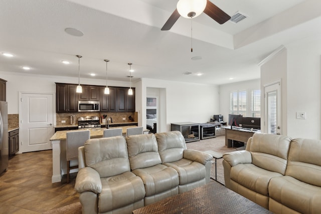 living area with a ceiling fan, recessed lighting, visible vents, and crown molding