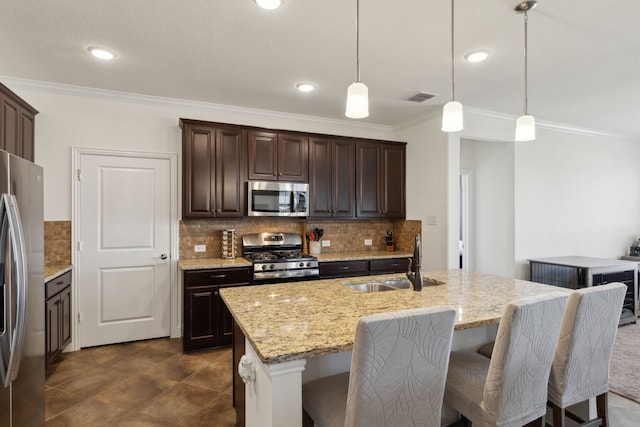 kitchen featuring dark brown cabinetry, a sink, ornamental molding, appliances with stainless steel finishes, and light stone countertops