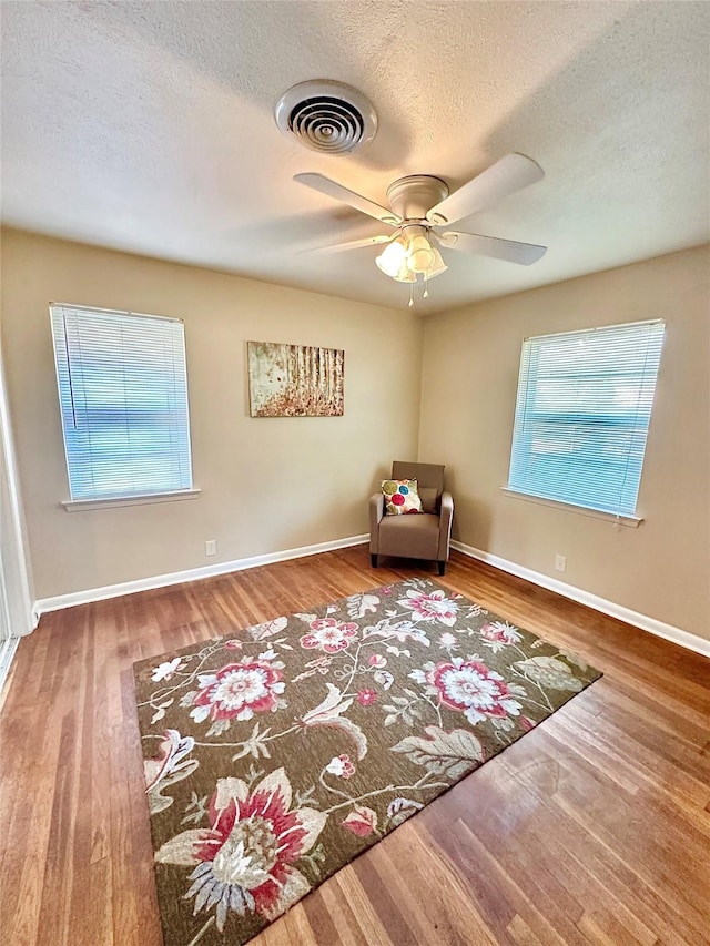 unfurnished room with plenty of natural light, visible vents, and wood finished floors