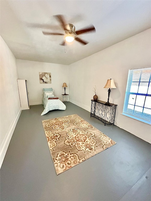 bedroom featuring a ceiling fan, finished concrete flooring, and baseboards