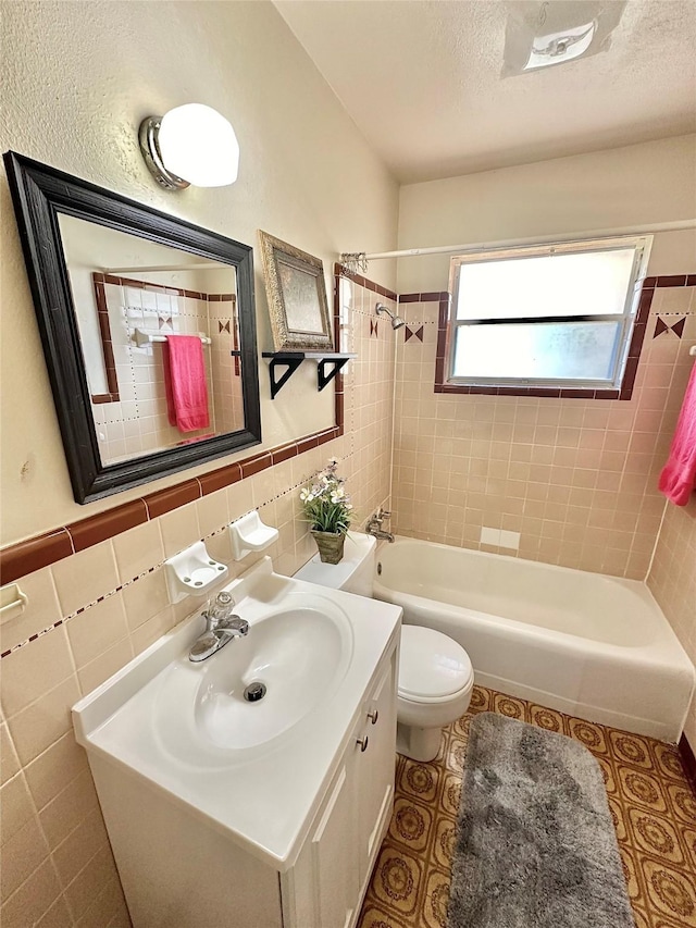 full bath with shower / bath combination, toilet, a textured ceiling, vanity, and tile walls