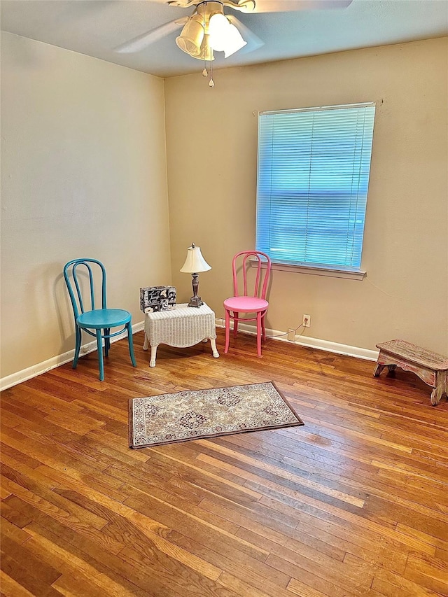 sitting room featuring wood-type flooring, baseboards, and a ceiling fan