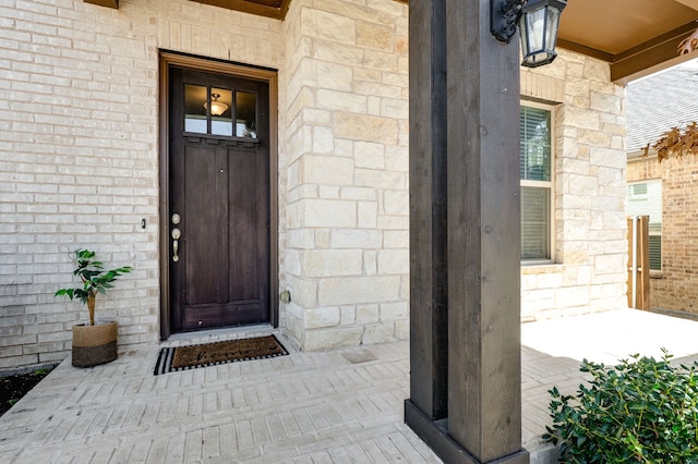 entrance to property featuring stone siding and brick siding