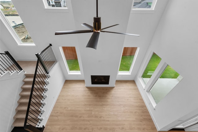 unfurnished living room featuring plenty of natural light, a fireplace, a high ceiling, and wood finished floors