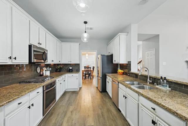 kitchen featuring visible vents, white cabinetry, stainless steel appliances, and a sink