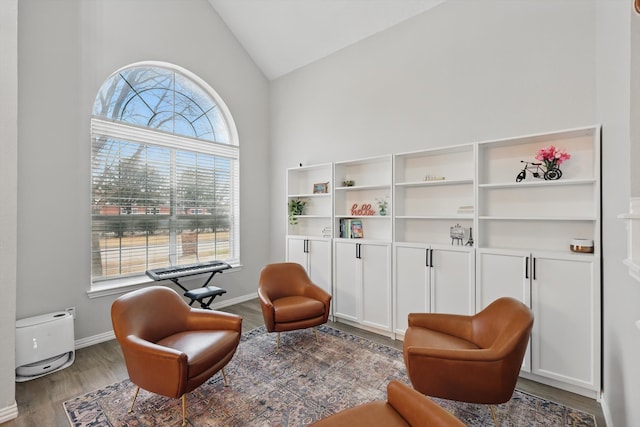 living area featuring lofted ceiling, baseboards, and wood finished floors