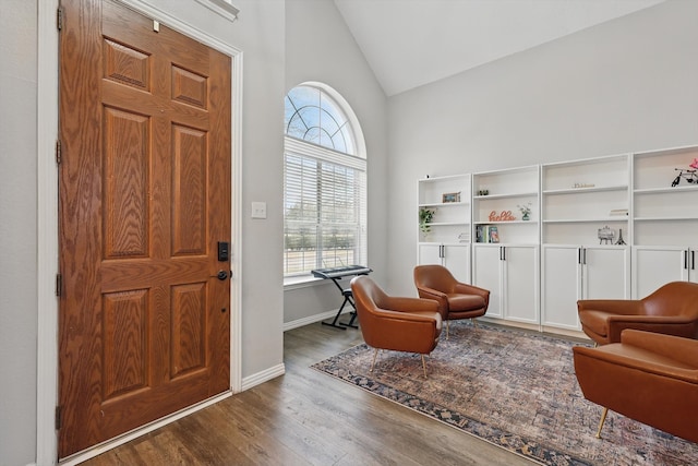 foyer entrance with lofted ceiling, baseboards, and wood finished floors