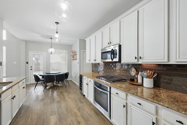 kitchen with appliances with stainless steel finishes, wine cooler, backsplash, and white cabinets