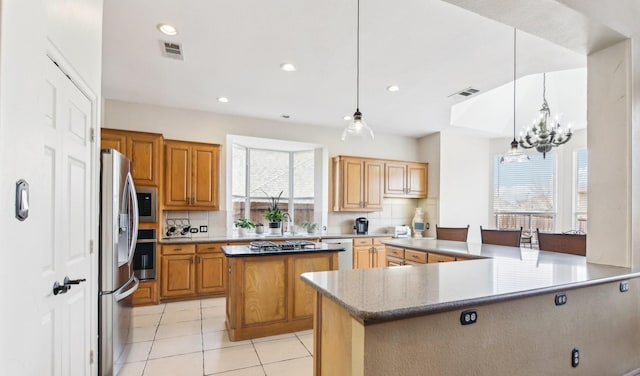 kitchen with appliances with stainless steel finishes, visible vents, decorative backsplash, and a center island