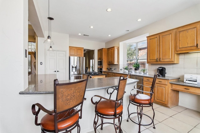 kitchen with stainless steel fridge, brown cabinetry, decorative backsplash, a kitchen bar, and recessed lighting