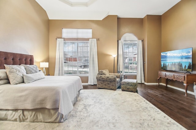 bedroom with multiple windows, baseboards, and wood finished floors