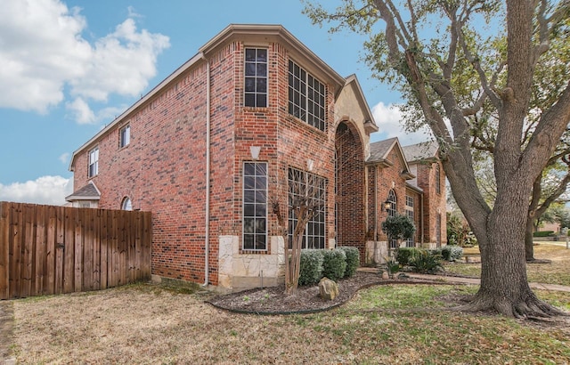 view of side of home featuring fence and brick siding