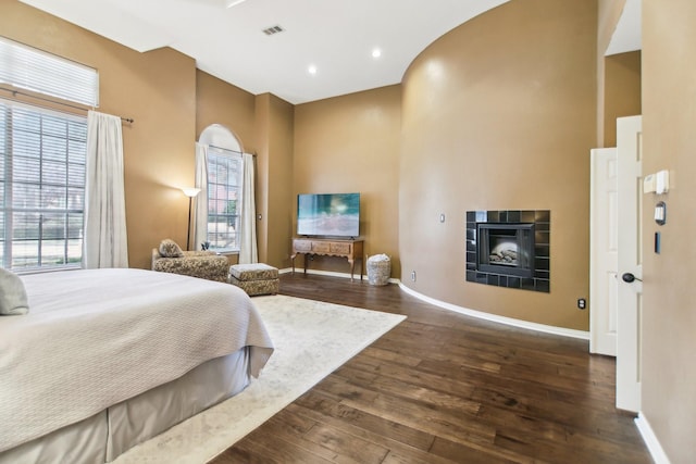 bedroom with baseboards, visible vents, dark wood-style flooring, and a tile fireplace