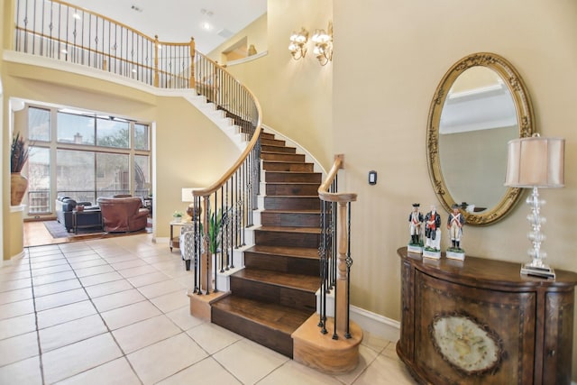 staircase with tile patterned flooring, a towering ceiling, and baseboards