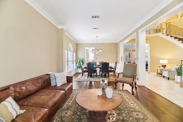 living room featuring a chandelier, visible vents, ornamental molding, and wood finished floors